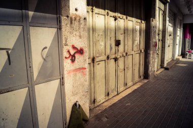 Hebron, Batı Şeria, 30 Ocak 2026 kapalı dükkan kepenkleri ve Hebron şehrinin caddesinde çift taraflı metal kapılar. Cuma günkü ticari kapanma sembolleri.