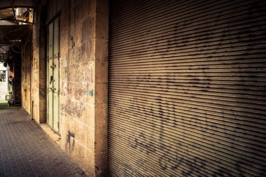 Hebron, Batı Şeria, 30 Ocak 2026 kapalı dükkan kepenkleri ve Hebron şehrinin caddesinde çift taraflı metal kapılar. Cuma günkü ticari kapanma sembolleri.