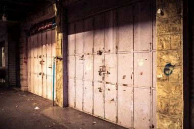 Hebron, Batı Şeria, 30 Ocak 2026 kapalı dükkan kepenkleri ve Hebron şehrinin caddesinde çift taraflı metal kapılar. Cuma günkü ticari kapanma sembolleri.