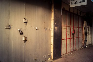 Hebron, Batı Şeria, 30 Ocak 2026 kapalı dükkan kepenkleri ve Hebron şehrinin caddesinde çift taraflı metal kapılar. Cuma günkü ticari kapanma sembolleri.