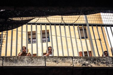 Hebron, Filistin Bölgesi, 31 Ocak 2026 Dikey Ayrımcılık. Üst katlardaki İsrailli göçmen çocuklar Filistin sokaklarına bakıyor. Metal ağ pazarı fırlatılan nesnelerden korur.
