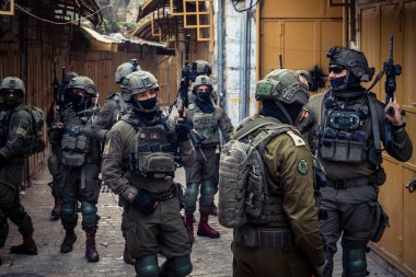 Hebron, Batı Şeria, Filistin. 14 Şubat 2026 'da İsrail askerleri Hebron' daki yerleşimcileri koruma altına aldı ve korudu. Hassas bir kentsel alanda savunma görevi.