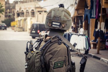 Hebron, Batı Şeria, Filistin. 14 Şubat 2026 İsrail askerleri göçmenlere eskortluk edip onları koruyorlar. Eski Filistin şehri El Halil 'in kalbindeki güvenlik ve düzeni bir ordu devriyesi sağlıyor..