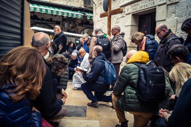 Kudüs, İsrail, 19 Şubat 2026 'da bir papazın yönettiği İtalyan Hristiyan hacılar Eski Şehir Via Dolorosa boyunca resmi bir geçit töreni düzenledi. Dindarlar dar sokaklarda haç taşır.