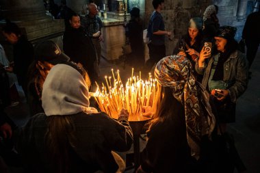 JERUSALEM, ISRAEL, 21 Şubat 2026 Hristiyan hacılar Kutsal Mezar Kilisesi 'nin mistik ve kutsal karanlığında dua mumları yakıyor. Ruhani atmosfer ve derin dinsel coşku.