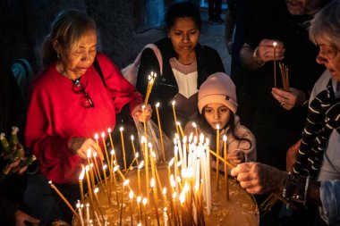 JERUSALEM, ISRAEL - 21 Şubat 2026 Hristiyan hacılar Kutsal Mezar Kilisesi 'nin mistik ve kutsal karanlığında dua mumları yaktılar. Ruhani atmosfer ve derin dinsel coşku.