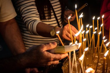JERUSALEM, ISRAEL - 21 Şubat 2026 Hristiyan hacılar Kutsal Mezar Kilisesi 'nin mistik ve kutsal karanlığında dua mumları yaktılar. Ruhani atmosfer ve derin dinsel coşku.