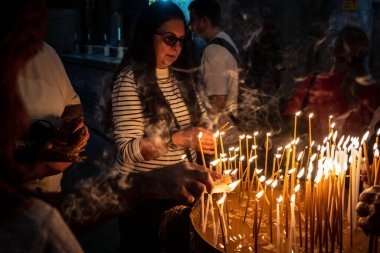 JERUSALEM, ISRAEL - 21 Şubat 2026 Hristiyan hacılar Kutsal Mezar Kilisesi 'nin mistik ve kutsal karanlığında dua mumları yaktılar. Ruhani atmosfer ve derin dinsel coşku.