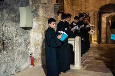 Kudüs, İsrail, 21 Şubat 2026 Katolik rahipler ve inananlar Kutsal Mezar 'ın karanlığında bir ayini kutluyorlar. Antik şehir tapınağındaki kutsal dua ve inanç atmosferi.