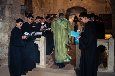 Kudüs, İsrail, 21 Şubat 2026 Katolik rahipler ve inananlar Kutsal Mezar 'ın karanlığında bir ayini kutluyorlar. Antik şehir tapınağındaki kutsal dua ve inanç atmosferi.