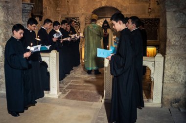 Kudüs, İsrail, 21 Şubat 2026 Katolik rahipler ve inananlar Kutsal Mezar 'ın karanlığında bir ayini kutluyorlar. Antik şehir tapınağındaki kutsal dua ve inanç atmosferi.