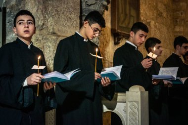 Kudüs, İsrail, 21 Şubat 2026 Katolik rahipler ve inananlar Kutsal Mezar 'ın karanlığında bir ayini kutluyorlar. Antik şehir tapınağındaki kutsal dua ve inanç atmosferi.