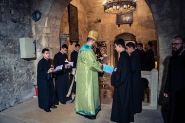 Kudüs, İsrail, 21 Şubat 2026 Katolik rahipler ve inananlar Kutsal Mezar 'ın karanlığında bir ayini kutluyorlar. Antik şehir tapınağındaki kutsal dua ve inanç atmosferi.