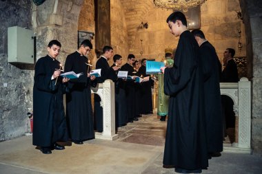 Kudüs, İsrail, 21 Şubat 2026 Katolik rahipler ve inananlar Kutsal Mezar 'ın karanlığında bir ayini kutluyorlar. Antik şehir tapınağındaki kutsal dua ve inanç atmosferi.