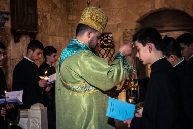 Kudüs, İsrail, 21 Şubat 2026 Katolik rahipler ve inananlar Kutsal Mezar 'ın karanlığında bir ayini kutluyorlar. Antik şehir tapınağındaki kutsal dua ve inanç atmosferi.