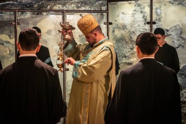 Kudüs, İsrail, 21 Şubat 2026 Katolik rahipler ve inananlar Kutsal Mezar 'ın karanlığında bir ayini kutluyorlar. Antik şehir tapınağındaki kutsal dua ve inanç atmosferi.