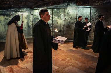 Kudüs, İsrail, 21 Şubat 2026 Katolik rahipler ve inananlar Kutsal Mezar 'ın karanlığında bir ayini kutluyorlar. Antik şehir tapınağındaki kutsal dua ve inanç atmosferi.