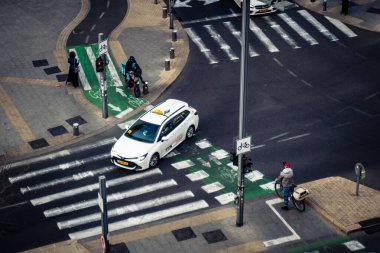 Tel Aviv, İsrail - 23 Şubat 2026: Şehir merkezinde yoğun bir kavşaktan geçen beyaz bir taksi. Şehir trafiği hafta içi Akdeniz Hitech metropolünün yüksek yoğunluk ve ekonomik faaliyetlerini yansıtıyor.