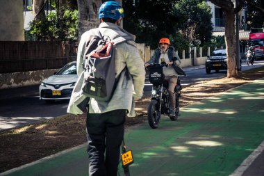 Tel Aviv, İsrail, 26 Şubat 2026, Rothschild Bulvarı 'nda elektrikli scooter kullanan insanlar, yoğun araba ve otobüs akışı, hareket halindeki elektrikli scooter' lar ve bisikletler, şehir yaşam enerjisi ve sokak dinamikleri, metropol desenleri ve ışık gözlemi
