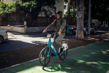 Tel Aviv, İsrail, 26 Şubat 2026, Rothschild Bulvarı 'nda bisiklet süren insanlar, yoğun araba ve otobüs akışı, hareket halindeki elektrikli scooter' lar ve bisikletler, şehir yaşam enerjisi ve sokak dinamikleri, metropolitan desenleri ve I.C.