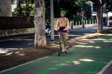 Tel Aviv, İsrail, 26 Şubat 2026, Rothschild Bulvarı 'nda elektrikli scooter kullanan insanlar, yoğun araba ve otobüs akışı, hareket halindeki elektrikli scooter' lar ve bisikletler, şehir yaşam enerjisi ve sokak dinamikleri, metropol desenleri ve ışık gözlemi