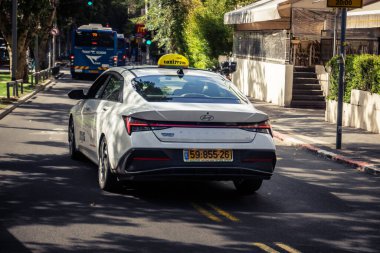 Tel Aviv, İsrail, 26 Şubat 2026, Sheinkin Caddesi 'nde Taksi, şehir trafiği, Bauhaus mimarisi geçmişi olan ikonik şehir ulaşımı, hareketli sokak aktivitesi, hareket halindeki araçlarda güneş ışığı, Göçmen Bürosu tarafından gözlemlenen ritmik geometri ve hareket