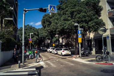 Tel Aviv, İsrail, 26 Şubat 2026, Sheinkin Caddesi Manzarası, şehir perspektifi, efsanevi Bauhaus çizgileri, beyaz cephelerdeki ritmik gölge desenleri, canlı şehir atmosferi, yoğun bakım ünitesinin gözlemlediği yapısal zarafet ve kademeli ışık..