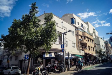 Tel Aviv, İsrail, 26 Şubat 2026, Sheinkin Caddesi Manzarası, şehir perspektifi, efsanevi Bauhaus çizgileri, beyaz cephelerdeki ritmik gölge desenleri, canlı şehir atmosferi, yoğun bakım ünitesinin gözlemlediği yapısal zarafet ve kademeli ışık..