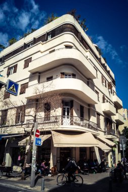 Tel Aviv, İsrail, 26 Şubat 2026, Sheinkin Caddesi Manzarası, şehir perspektifi, efsanevi Bauhaus çizgileri, beyaz cephelerdeki ritmik gölge desenleri, canlı şehir atmosferi, yoğun bakım ünitesinin gözlemlediği yapısal zarafet ve kademeli ışık..