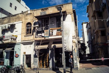 Tel Aviv, İsrail, 26 Şubat 2026, Sheinkin Caddesi Manzarası, şehir perspektifi, efsanevi Bauhaus çizgileri, beyaz cephelerdeki ritmik gölge desenleri, canlı şehir atmosferi, yoğun bakım ünitesinin gözlemlediği yapısal zarafet ve kademeli ışık..