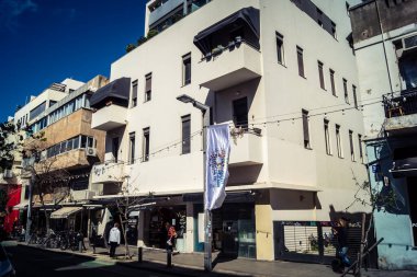 Tel Aviv, İsrail, 26 Şubat 2026, Sheinkin Caddesi Manzarası, şehir perspektifi, efsanevi Bauhaus çizgileri, beyaz cephelerdeki ritmik gölge desenleri, canlı şehir atmosferi, yoğun bakım ünitesinin gözlemlediği yapısal zarafet ve kademeli ışık..