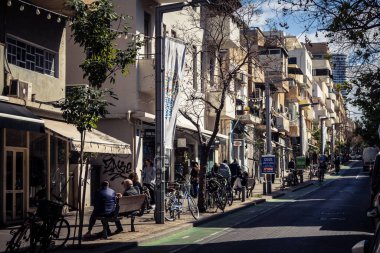 Tel Aviv, İsrail, 26 Şubat 2026, Sheinkin Caddesi Manzarası, şehir perspektifi, efsanevi Bauhaus çizgileri, beyaz cephelerdeki ritmik gölge desenleri, canlı şehir atmosferi, yoğun bakım ünitesinin gözlemlediği yapısal zarafet ve kademeli ışık..