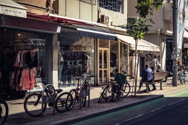 Tel Aviv, İsrail, 26 Şubat 2026, Sheinkin Caddesi Manzarası, şehir perspektifi, efsanevi Bauhaus çizgileri, beyaz cephelerdeki ritmik gölge desenleri, canlı şehir atmosferi, yoğun bakım ünitesinin gözlemlediği yapısal zarafet ve kademeli ışık..