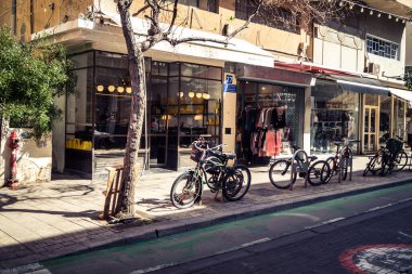 Tel Aviv, İsrail, 26 Şubat 2026, Sheinkin Caddesi Manzarası, şehir perspektifi, efsanevi Bauhaus çizgileri, beyaz cephelerdeki ritmik gölge desenleri, canlı şehir atmosferi, yoğun bakım ünitesinin gözlemlediği yapısal zarafet ve kademeli ışık..