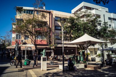 Tel Aviv, İsrail, 26 Şubat 2026, Sheinkin Caddesi Manzarası, şehir perspektifi, efsanevi Bauhaus çizgileri, beyaz cephelerdeki ritmik gölge desenleri, canlı şehir atmosferi, yoğun bakım ünitesinin gözlemlediği yapısal zarafet ve kademeli ışık..