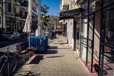 Tel Aviv, İsrail, 26 Şubat 2026, Sheinkin Caddesi Manzarası, şehir perspektifi, efsanevi Bauhaus çizgileri, beyaz cephelerdeki ritmik gölge desenleri, canlı şehir atmosferi, yoğun bakım ünitesinin gözlemlediği yapısal zarafet ve kademeli ışık..