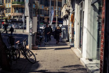 Tel Aviv, İsrail, 26 Şubat 2026, Sheinkin Caddesi Manzarası, şehir perspektifi, efsanevi Bauhaus çizgileri, beyaz cephelerdeki ritmik gölge desenleri, canlı şehir atmosferi, yoğun bakım ünitesinin gözlemlediği yapısal zarafet ve kademeli ışık..