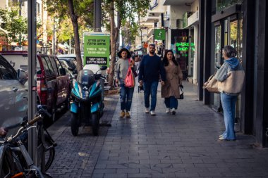 Tel Aviv, İsrail, 26 Şubat 2026, Sheinkin Caddesi 'nde yürüyen yayalar, dinamik hareketli canlı şehir manzarası, arkaplan olarak Bauhaus mimarisi, canlı şehir yaşamı, çeşitli sokak dokularında güneş ışığı, ritmik geometri ve çağlayan ışık obse