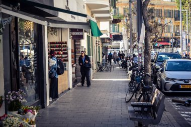 Tel Aviv, İsrail, 26 Şubat 2026, Sheinkin Caddesi Manzarası, şehir perspektifi, efsanevi Bauhaus çizgileri, beyaz cephelerdeki ritmik gölge desenleri, canlı şehir atmosferi, yoğun bakım ünitesinin gözlemlediği yapısal zarafet ve kademeli ışık..