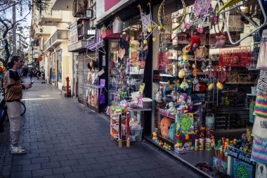 Tel Aviv, İsrail, 26 Şubat 2026, Sheinkin Caddesi Manzarası, şehir perspektifi, efsanevi Bauhaus çizgileri, beyaz cephelerdeki ritmik gölge desenleri, canlı şehir atmosferi, yoğun bakım ünitesinin gözlemlediği yapısal zarafet ve kademeli ışık..