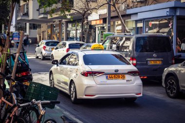 Tel Aviv, İsrail, 26 Şubat 2026, Sheinkin Caddesi 'nde Taksi, şehir trafiği, Bauhaus mimarisi geçmişi olan ikonik şehir ulaşımı, hareketli sokak aktivitesi, hareket halindeki araçlarda güneş ışığı, Göçmen Bürosu tarafından gözlemlenen ritmik geometri ve hareket