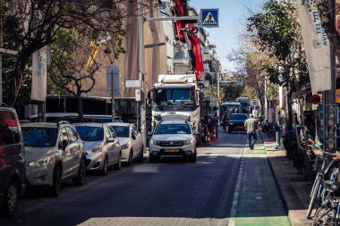 Tel Aviv, İsrail, 26 Şubat 2026, Sheinkin Caddesi Manzarası, şehir perspektifi, efsanevi Bauhaus çizgileri, beyaz cephelerdeki ritmik gölge desenleri, canlı şehir atmosferi, yoğun bakım ünitesinin gözlemlediği yapısal zarafet ve kademeli ışık..