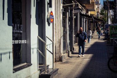 Tel Aviv, İsrail, 26 Şubat 2026, Sheinkin Caddesi 'nde yürüyen yayalar, dinamik hareketli canlı şehir manzarası, arkaplan olarak Bauhaus mimarisi, canlı şehir yaşamı, çeşitli sokak dokularında güneş ışığı, ritmik geometri ve çağlayan ışık obse