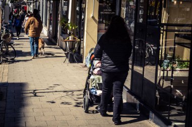 Tel Aviv, İsrail, 26 Şubat 2026, Sheinkin Caddesi 'nde yürüyen yayalar, dinamik hareketli canlı şehir manzarası, arkaplan olarak Bauhaus mimarisi, canlı şehir yaşamı, çeşitli sokak dokularında güneş ışığı, ritmik geometri ve çağlayan ışık obse