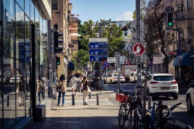 Tel Aviv, İsrail, 26 Şubat 2026, Sheinkin Caddesi Manzarası, şehir perspektifi, efsanevi Bauhaus çizgileri, beyaz cephelerdeki ritmik gölge desenleri, canlı şehir atmosferi, yoğun bakım ünitesinin gözlemlediği yapısal zarafet ve kademeli ışık..