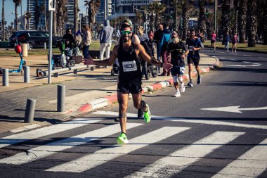 Tel Aviv, İsrail, 27 Şubat 2026 Bir katılımcı doğrudan göz teması kuruyor ve kameraya el sallıyor. Şehir maratonu sırasında kişisel bir bağlantı ve dayanıklılık anı yakalıyor..