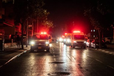 Tel Aviv, İsrail, 1 Mart 2026 Tel Aviv şehir merkezindeki bir füze sahasında acil durum ekipleri ve güvenlik güçlerinin görüntüsü, sağlık görevlileri ve itfaiyeciler enkaz ve parçalanmış camlar arasında yardım sağlıyorlar.