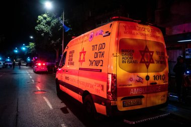 Tel Aviv, İsrail, 1 Mart 2026 Tel Aviv şehir merkezindeki bir füze sahasında acil durum ekipleri ve güvenlik güçlerinin görüntüsü, sağlık görevlileri ve itfaiyeciler enkaz ve parçalanmış camlar arasında yardım sağlıyorlar.