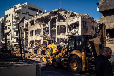 Tel Aviv, İsrail, 1 Mart 2026. Tel Aviv şehir merkezindeki bir füze saldırısından bir gün sonra belediye çalışanları ve sakinleri enkaz ve cam kırıkları arasında meydana gelen hasarları değerlendirerek bölgede güvenlik çemberi oluşturulmaya başlandı..