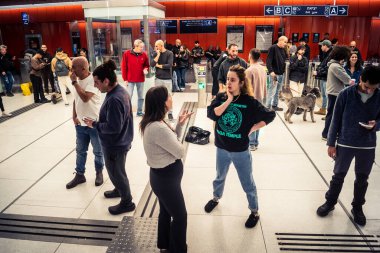 Tel Aviv, İsrail, 5 Mart 2026 'da vatandaşlar Tel Aviv metro istasyonunun güçlendirilmiş yeraltı katlarında güvenlik önlemleri alınarak bomba sığınağına dönüştürülmesini bekliyorlar. Siviller yürüyen merdivenlerin yanında toplanır ve İbranice işaretleri takip ederek sa 'yı korurlar.